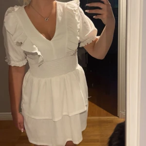 Vit volangklänning  - Supersöt vit kort klänning med v-ringning, puffärmar och volangdetaljer från Gina tricot!🤍använd 1 gång!🤍