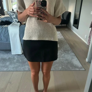 Svart kortkjol i enkel modell - En stilren svart kortkjol med rak passform och minimalistisk design. Kjolen är enfärgad och har en klassisk look som är lätt att matcha med olika toppar. Perfekt för dig som gillar en clean och tidlös stil.