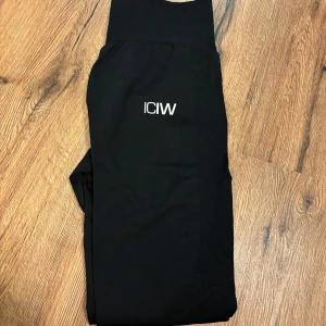 Svarta leggings från ICANIWILL - Svarta leggings från ICANIWILL med hög midja och diskret logga framtill. Snygg och tight passform, perfekta för träning eller chill. Tillverkade i stretchigt syntetmaterial som andas.
