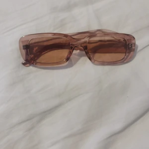 Rosa rektangulära solglasögon Monki - Snygga solglasögon från Monki i transparent rosa plast med rektangulära bågar. Lätta och bekväma att bära, passar till alla tillfällen när solen skiner☀️Har ej avänt de