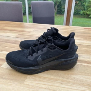 Svarta Nike sneakers med mesh - Snygga helsvarta Nike sneakers med mesh-ovandel och robust sula. Skorna har klassisk snörning och diskret Nike-logga på sidan. Perfekta för dig som gillar stilrena och sportiga skor med bekväm passform. Nästintill oanvända och i storlek 44.