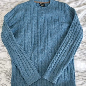 Blå kabelstickad tröja Massimo Dutti - Kabelstickad blå tröja från Massimo Dutti i en mjuk mix av ull och kashmir. Tröjan har rund halsringning, ribbade muddar och lång ärm. Perfekt för dig som gillar klassisk stil med en modern touch.