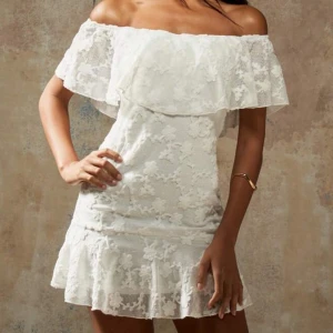 Vit offshoulder spetsklänning - Superfin vit kortklänning med offshoulder och volangdetaljer. Klänningen har blommigt spetsmönster och en figurnära passform som ger en romantisk vibe. Perfekt för sommarens alla tillfällen! Använd endast en gång annars helt ny! Passar XS-S
