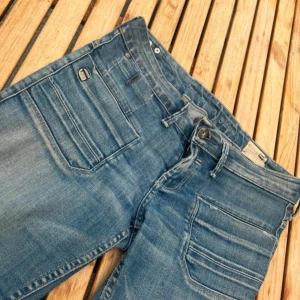 Lågmidjade jeans - Säljer ett par klassiska blå jeans som är bootcut. Jeansen har flera fickor fram och bak, dragkedja i gylfen och coola kontrastsömmar. Perfekta för en avslappnad streetstil och tillverkade i tåligt denimtyg.