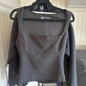 Svart linnetopp från Zara - Svart linnetopp från Zara med breda axelband och fyrkantig urringning. Snygg, stilren och figurnära passform som ger en clean look. Perfekt att matcha med jeans eller kjol för en trendig vibe. Materialet känns mjukt och har lite stretch.