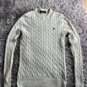 Vit kabelstickad Morris tröja  - Snygg vit kabelstickad tröja från Morris med rund hals och diskret logga broderad på bröstet. 