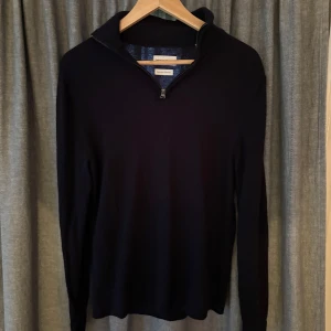 Mörkblå merinoulltröja These Glory Days - Snygg mörkblå långärmad tröja från These Glory Days i mjuk superior merinoull. Tröjan har en stilren half zip-dragkedja vid kragen och sitter normal/slim på kroppen. Perfekt för dig som gillar minimalistisk och clean stil.