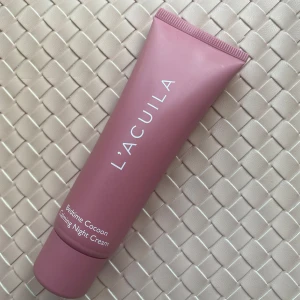 L'Acuila Bedtime Cocoon Night Cream - Säljer en Bedtime Cocoon Calming Night Cream från L'Acuila i en snygg rosa tub. Perfekt för dig som vill ha en återfuktande och lugnande nattkräm med stilren design. Tuben är smidig att ta med och har en modern look. 🫶🫶