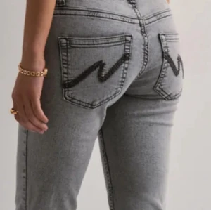 Low waist, grå bootcut jeans från Nelly - Snygga grå jeans med bootcut passform och coola svarta broderier på bakfickorna. De har låg midja, dubbla knappar fram och klassisk femficksdesign. ANVÄNT ENDAS EN GÅNG          Kan gå ner i priset vid snabb affär 