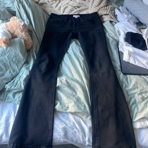 Svarta bootcut jeans från Gina Tricot - De passar perfekt på mig som har 72 i midjemått och är 164, de är Snygga svarta jeans från Gina Tricot i bootcut-modell med normal passform. Jeansen har klassisk femficksdesign, bälteshällor och dragkedja. Bakfickorna är dekorerade med silvriga nitar som ger en cool touch. Perfekta för dig som gillar stilrena och trendiga jeans.