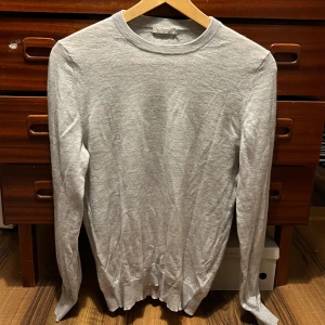 Ljusgrå kashmirtröja från Suitsupply -  Ljusgrå/Vit  tunnare Kashmir tröja från Suitsupply. I nyskick som bara är använd ett fåtal gånger som är perfekt nu till hösten 