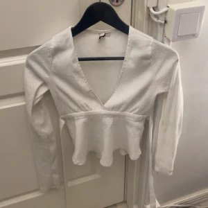 Vit v-ringad blus med volang - Säljer min vita tröja från Nelly. Knyts i ryggen eller framtill, använd få tal gånger.