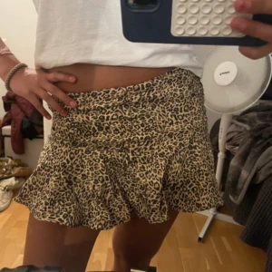 Leopardmönstrad volangkjol från Zara - Supersnygg kort kjol från Zara med leopardmönster i beige, svart och brunt. Kjolen har volangkant som ger en extra flirty vibe och sitter normalt i midjan. Perfekt för dig som vill sticka ut med ett djuriskt print.
