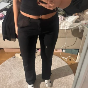 Svarta bootcut kostymbyxor - Snygga svarta kostymbyxor med bootcut och låg midja. Byxorna har klassisk rak passform och är perfekta för en clean och stilren look. Materialet känns mjukt och följsamt, vilket gör dem bekväma att bära hela dagen. Passar dig som gillar minimalistisk stil.