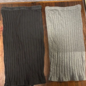 Ribbad svart och grå kjol - Två snygga ribbade kjolar i svart och grått. Båda har en rak, lång siluett med vertikala ribbade detaljer som ger en cool och modern look. Perfekt att matcha med en enkel topp eller hoodie för en chill stil.