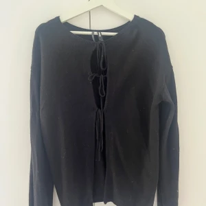 Svart kofta med snörning från Bik Bok - Svart kofta från Bik Bok i mjuk ull- och kashmirblandning. Koftan har lång ärm och snygg snörning framtill som ger en cool och trendig look. Perfekt att slänga över en topp för en chill vibe. Materialet är 40% ull, 30% viskos, 20% polyamid och 10% kashmir.