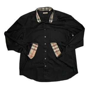 Svart Burberry skjorta med rutiga detaljer - Svart skjorta från Burberry med klassiska rutiga detaljer på insidan av kragen och manschetterna. Skjortan har lång ärm, knappar framtill och en stilren, tidlös look. Perfekt för dig som gillar en clean men ändå lyxig stil. Storleken är M och skicket är bra !