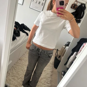 Grå bootcut jeans med låg midja - Säljer ett par grå jeans med låg midja och bootcut-ben. Jeansen har klassiska fickor fram och bak, snygga sömdetaljer och en cool tvättad look. Perfekta för dig som gillar en avslappnad men trendig stil.