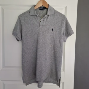 Grå pikétröja från Polo Ralph Lauren - Snygg grå pikétröja från Polo Ralph Lauren i custom fit. Tröjan är nästan aldrig använd. Priset kan diskuteras!
