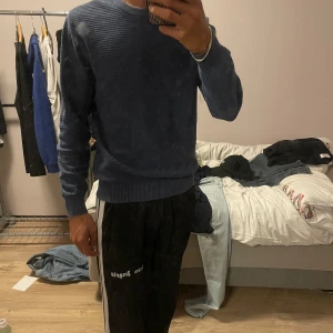 Blå ribbad tröja från Dressmann - Säljer en blå ribbad tröja från Dressmann i storlek S. Tröjan har rund hals, långärmade ärmar och är tillverkad i mjukt stickat material. Den har en clean look med diskreta horisontella ränder och breda muddar vid ärmslut och nederkant. Perfekt för dig som gillar enkel och stilren design.