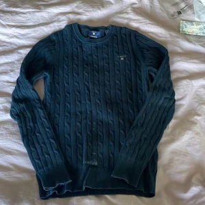 Mörkblå kabelstickad tröja GANT XS - Snygg mörkblå kabelstickad tröja från GANT i stretchig bomull. Vit färgfläck på magen, vet inte om det går att få bort den på något sätt. Pris går absolut att diskutera med tanke på färg fläcken💕