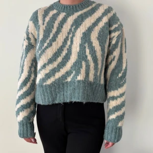 Grön och vit zebramönstrad stickad tröja från Zara - Säljer en stickad tröja från Zara i grönt och vitt med zebramönster. Tröjan har croppad passform, rund halsringning och långa ärmar. Perfekt för dig som vill sticka ut med ett coolt mönster.