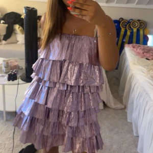 Lila glittrig volangklänning - Lila glittrig kortklänning från collective the label, med flera lager volanger. Klänningen har tunna axelband. Den är helt oanvänd med lappen kvar. Storlek 36💕