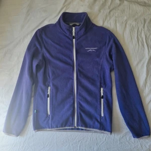 Lila Fleecetröja  - En jättefin lila fleecejacka med dragkedja. Två fickor med dragkedja på utsidan och två fickor på insidan. Mysig o skön!