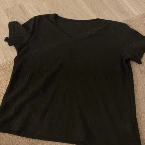 Svart ribbad kortärmad topp - En svart ribbad topp med v-ringning och korta ärmar. 