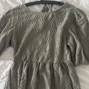 Mörkgrön blus från ginatricot - Fin blus från ginatricot, öppen rygg med knyt och puff axlar, jättefin & aldrig använd pga för liten 