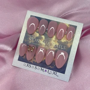 Blush (L);Short Almond - Snygga handgjorda press-on naglar i nude-rosa färg med  en roseguldig rosett på en nagel. Mandelformade och glansiga, perfekta för att ge en chic look. Kommer i storlek L: 17 mm, 12,5 mm, 13 mm, 12 mm, 10 mm ,  är enkla att applicera hemma.