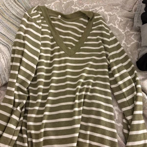 Randig grön och vit långärmad tröja - Säljer en chill långärmad tröja med gröna och vita ränder. Tröjan har en snygg v-ringad hals och är gjord i mjukt material som känns skönt mot huden. Perfekt för dig som gillar enkel och stilren design med lite edge.