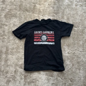 Svart Saint Laurent t-shirt med tryck - Svart t-shirt från Saint Laurent i storlek S. Tröjan är i mycket bra skick och har inget som är trasigt 