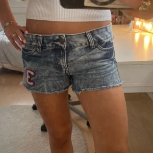 Blå jeansshorts från Diva med patch - Snygga blå jeansshorts med många saker som händer på den med en cool look och tvätt, inget slitage på dom förutom vid shortsens slut där det e meningen att dom ska vara så! Shortsen har använts 1-2 gånger så mycket bra! 