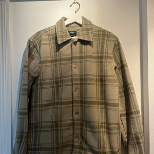 Varm rutig overshirt, perfekt till höst  - Beige och grön rutig overshirt, klassisk krage och knäppning framtill.  Overshirten är långärmad och tillverkad i mjukt fleecematerial,