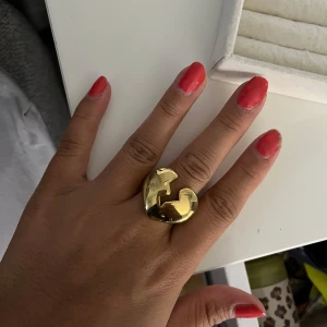 Guldfärgad chunky hjärtring - Cool och chunky ring i guldfärg med ett stort hjärta som har en bruten design. Ringen har en blank finish och är riktigt statement på fingret. Perfekt för dig som gillar att sticka ut med dina accessoarer och vill ha något som syns.