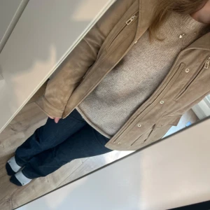 Beige mockajacka från Desigual - Snygg beige mockajacka från desigual med dragkedja och knappar. Jackan har flera fickor och en klassisk krage. Perfekt för en stilren look. Nypris är 1700kr