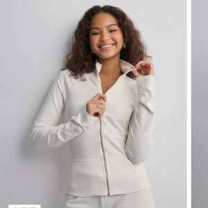 Vit långärmad tröja med dragkedja - Snygg och bekväm vit tröja med dragkedja framtill. Perfekt för en stilren look, med långa ärmar och hög krage. Passar bra till både träning och vardag. Slutsåld i storlek xs