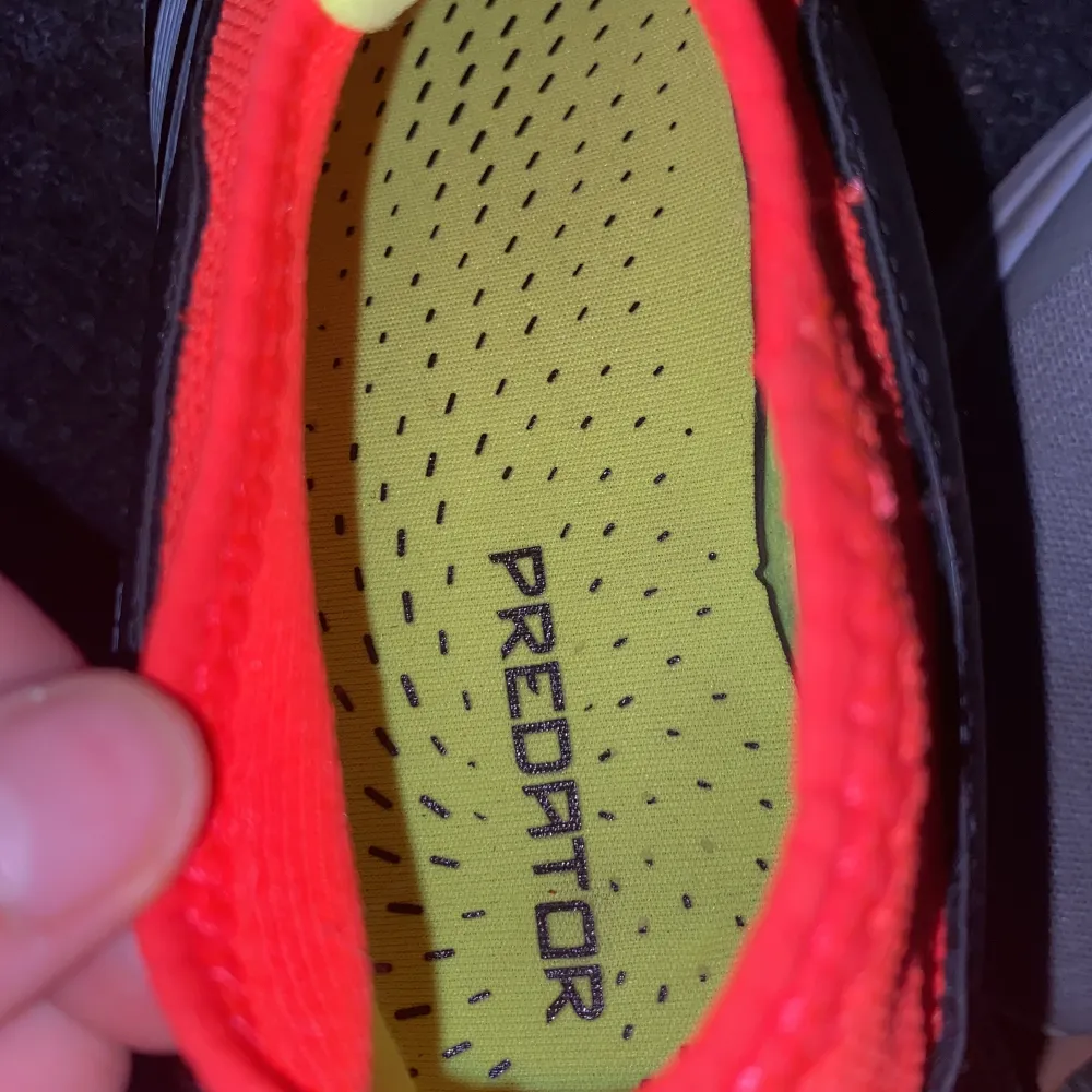 STÄDAS INNAN Skickning Snygga Adidas Predator fotbollsskor i svart, vitt och rött. Skorna har en modern design med tydliga ränder och dobbar för bra grepp på planen. Perfekta för fotbollsspelare som vill ha stil och funktion.. Kengät.