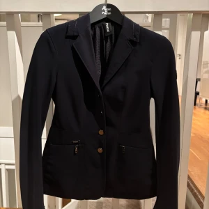 Ryttare, se hit! Marinblå kavaj från Pikeur - Snygg marinblå kavaj från Pikeur med snygga och lite glittriga detaljer. Använd fåtal gånger på tävling, så i väldigt fint skick. Nypris strax över 3 500 kr. Priset är diskuterbart!