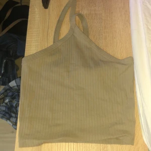 Beige ribbad linnetopp från Gina Tricot - Säljer en snygg beige ribbad linnetopp från Gina Tricot. Toppen har smala axelband och en stilren design som passar perfekt till sommaren. Perfekt för att matcha med jeans eller kjol för en avslappnad look.