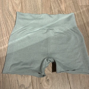 Grå shorts med hög midja - Snygga grå shorts med hög midja och ribbade detaljer på sidorna. Perfekta för träning eller en avslappnad dag. De har en tight passform som ger bra stöd och komfort.