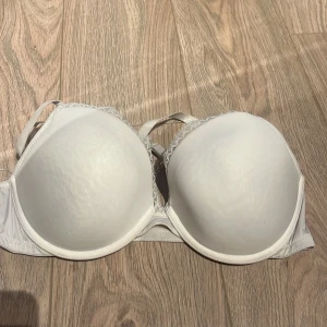Vit bh med spetsdetaljer - Säljer en vit bh med spetsdetaljer på sidorna. Den har vadderade kupor och justerbara axelband för bästa passform. Perfekt för att ge extra stöd och komfort.