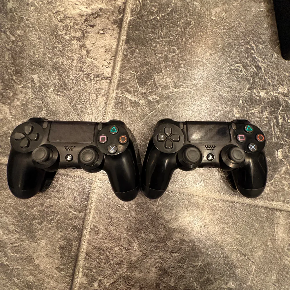 Säljer en PlayStation 4 med två svarta DualShock 4-handkontroller. Konsolen har en stilren design och kommer med nödvändiga kablar. Perfekt för gamingkvällar med vänner! 🎮. Asusteet.