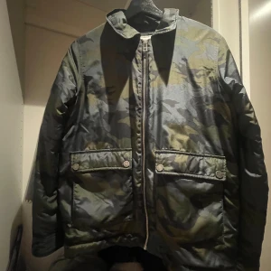 Grön jacka med dragkedja - Säljer en cool jacka i camouflage-mönster med dragkedja framtill, ifrån Zadig&Voltaire. Jackan har långa ärmar och praktiska fickor med knappar. Perfekt som vårjacka💕Skulle uppskatta storlek XS/S! Hör gärna av er om ni önskar fler bilder eller mer info💕