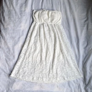 Vit spetsklänning  - Säljer en söt vit axelbandslös klänning från Size 8 Needle. Klänningen är täckt i spets och har en luftig passform som är perfekt för varma dagar. Den är axelbandslös och har en elastisk överdel för extra komfort. Perfekt för sommarens alla tillfällen! 🌸 Helt ny ned prislapp kvar.