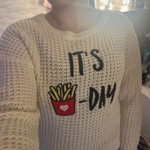 Vit stickad tröja med tryck - Säljer en vit stickad tröja från Primark med ett roligt tryck av pommes och texten 'IT'S 🍟-DAY'. Tröjan har en avslappnad passform och långa ärmar, perfekt för en mysig dag hemma. 🥰