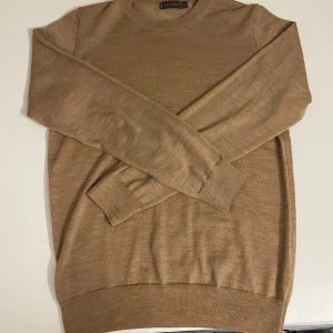 Beige tröja från Oscar Jacobson - Säljer en stilren beige tröja från Oscar Jacobson, tillverkad i Italien. Tröjan har en klassisk design med långa ärmar och ribbade muddar vid ärmslut och nederkant. Perfekt för en elegant och avslappnad look. Nypris 1500 mitt 699. Tröjans inre lapp lossnade lite men är sydd och märks inte utifrån. Passar xs och s.