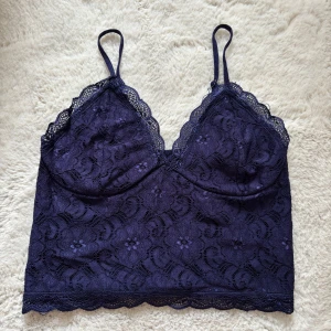 Mörkblå crop top - Säljer ett vackert mötkblått spetslinne med justerbara axelband. Toppen har ett blommigt spetsmönster och en elastisk rygg för extra komfort.