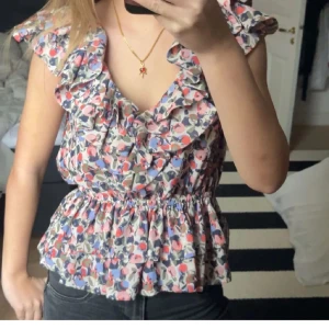 Blommig blus med volanger - Säljer en söt blommig blus med volanger och elastisk midja. size S. perfekt för sommar.